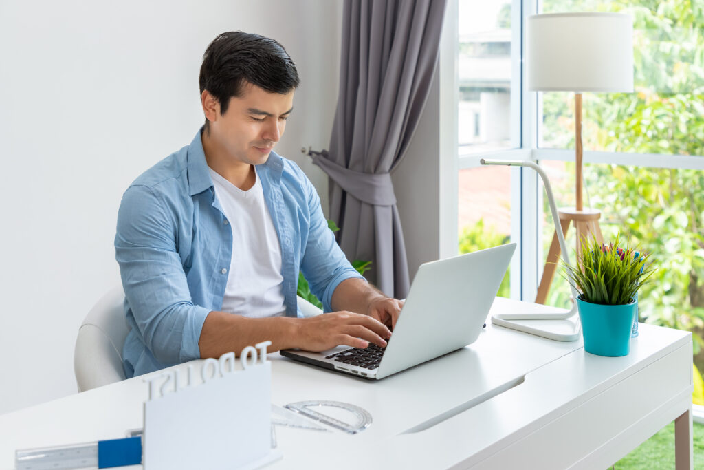 attractive man is working home using laptop computer notebook