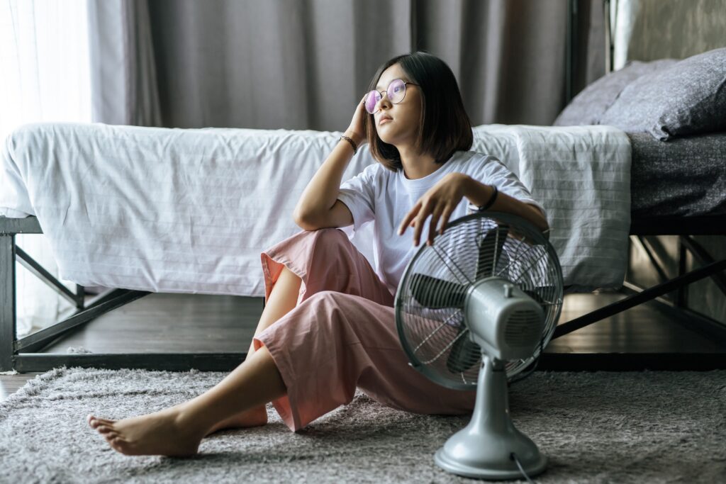 woman wore white shirt hand placed table fan looked out 1
